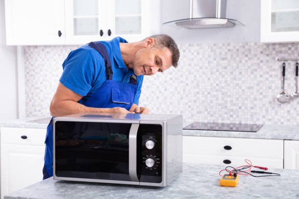 Side View Of Mature Man Repairing Microwave Oven In Kitchen